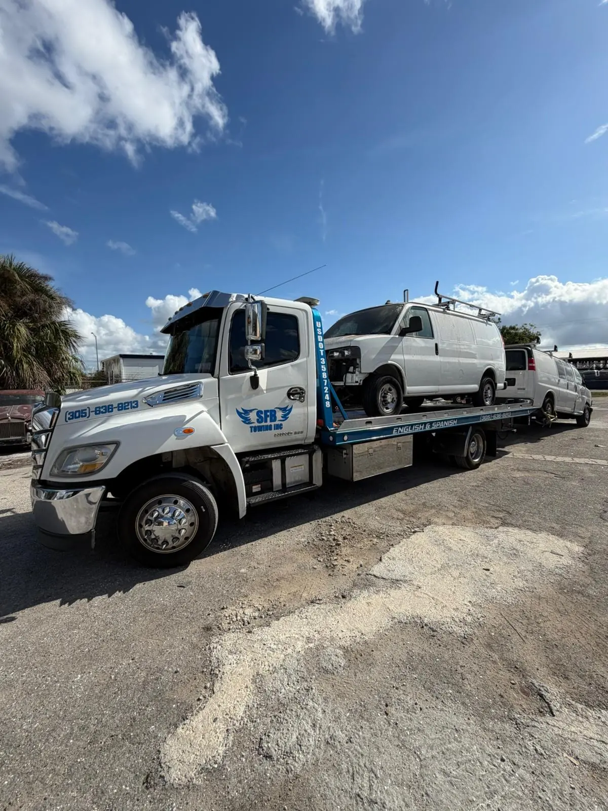 SFB Towing flatbed with a cargo van on the bed at a commercial site