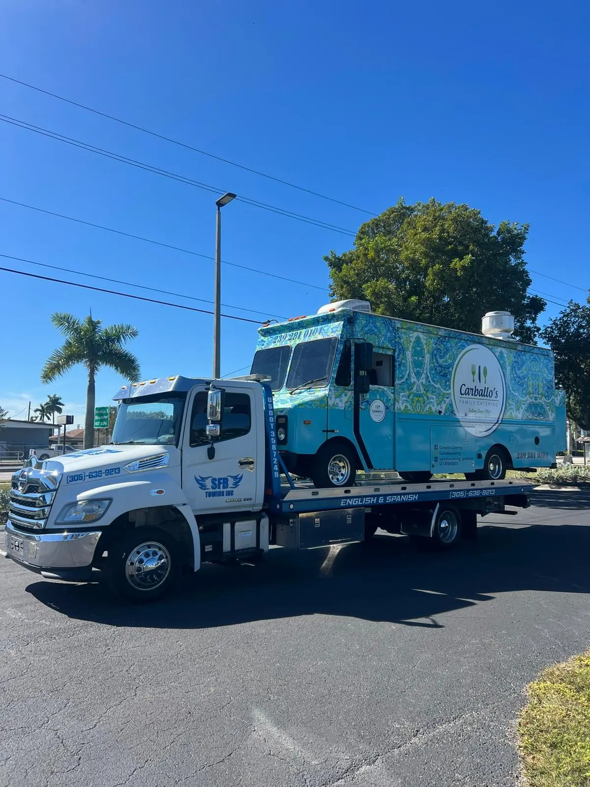 SFB Towing flatbed with a turquoise mobile food truck on the bed