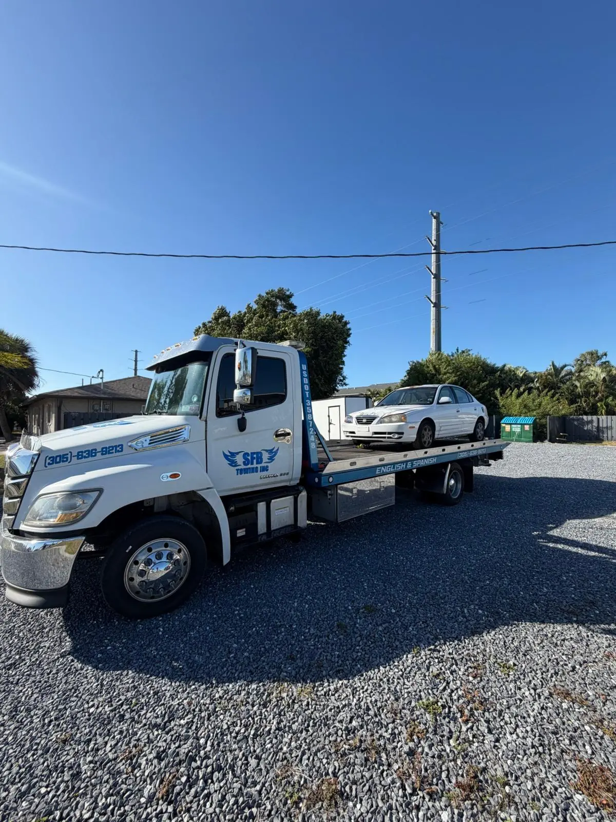 SFB Towing flatbed with a sedan on the bed on a sunny day