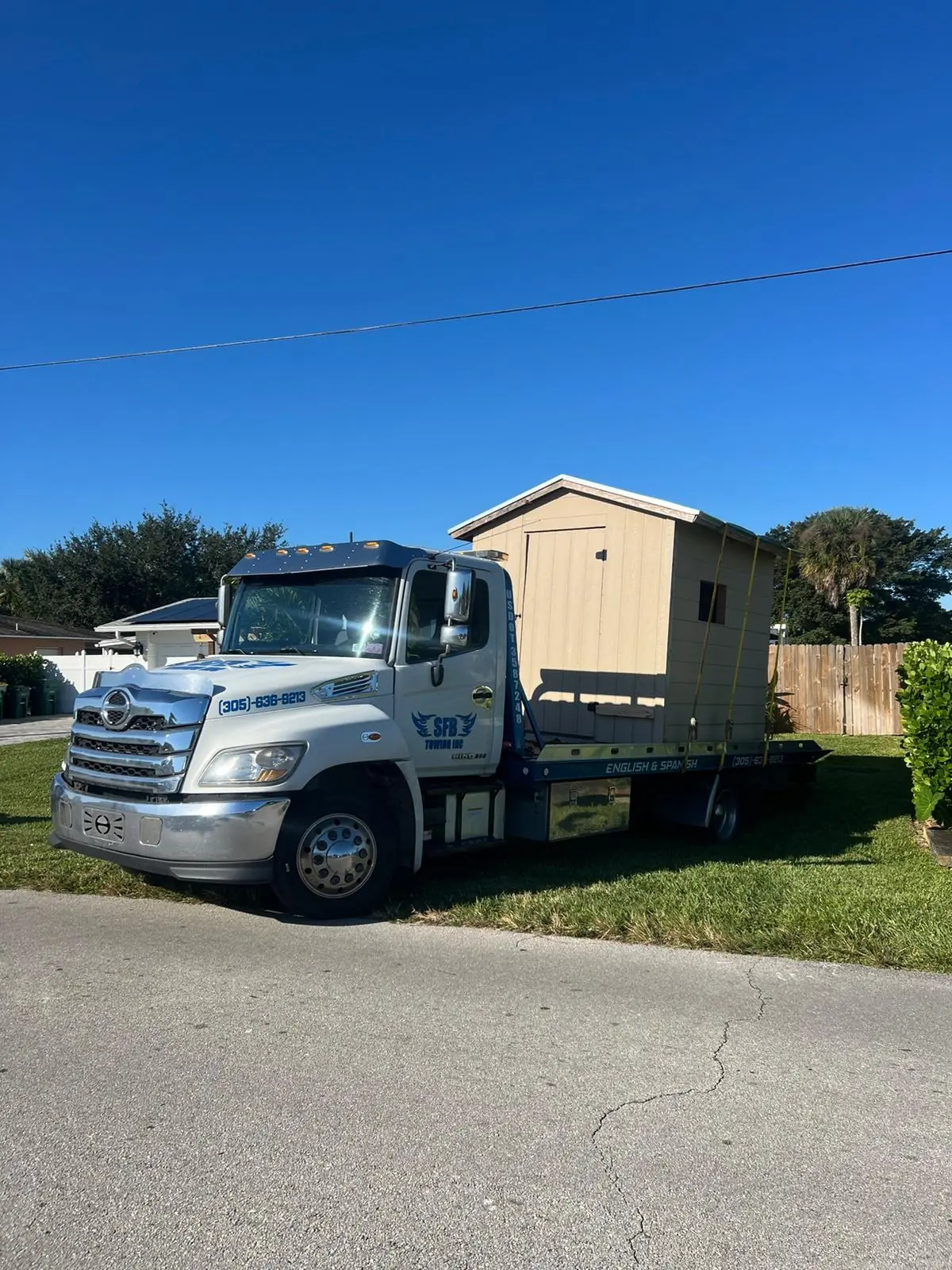 SFB Towing flatbed delivering a wood storage shed to a residential yard